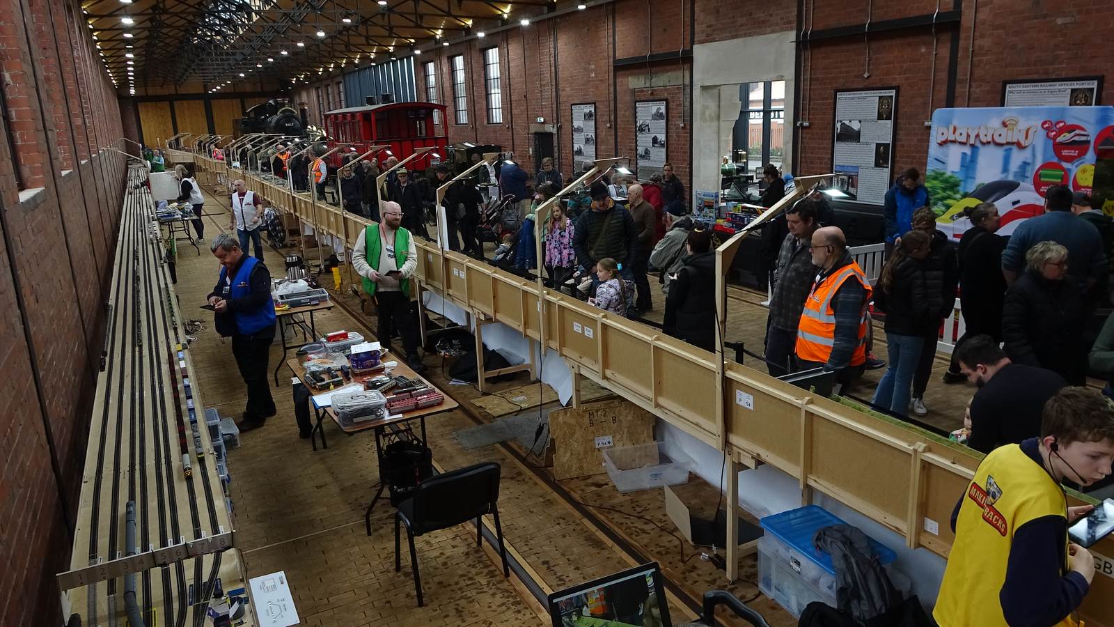 The Making Tracks layout running the full length of an engine shed, crew in hi-vis among the visitors